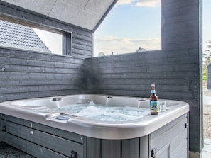 A hot tub with a bottle of beer, wooden walls, and a window. - 5 Star Holiday Home in Romo (Rømø)