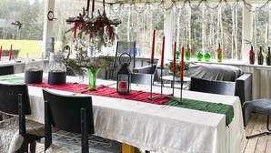 An outdoor dining area with tables covered in white tablecloths, red and green placemats, and candle holders. - 7 Person Holiday Home in Nassjo (Nassjo)