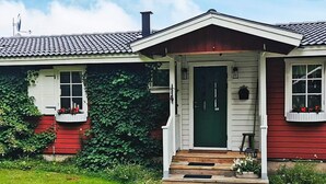 A house with a green door, white trim, and red siding. There is a small porch with steps leading to the door. - 7 Person Holiday Home in Nassjo (Nassjo)