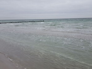 En strand med bølger og en bølgebryder af træ.