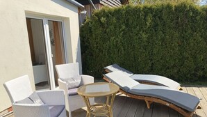 A patio with wicker chairs, a small round table, and two lounge chairs with cushions. - Fabian Comfortable Holiday Residence (Wieck auf dem Darss)
