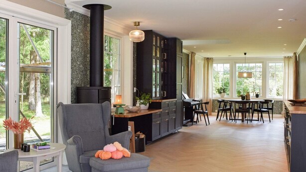 Amplia sala de estar con chimenea, un piano y una mesa de comedor con sillas.