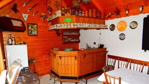 Un intérieur rustique en bois, avec un coin bar, des chaises en bois et une table à manger.