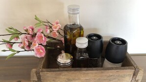 A wooden crate containing various bottles and a branch with pink flowers. - Holiday Apartment III Bjork (Münchehofe)
