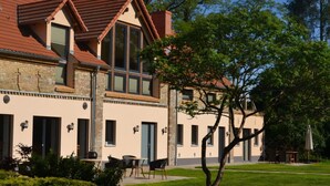 A two-story building with a red-tiled roof, large windows, and a well-maintained lawn. - Holiday Apartment III Bjork (Münchehofe)