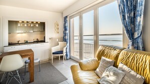 A modern living room with a sofa, a dining table, and a kitchen area. - Nevada Apartment Near the Beach (Koksijde)