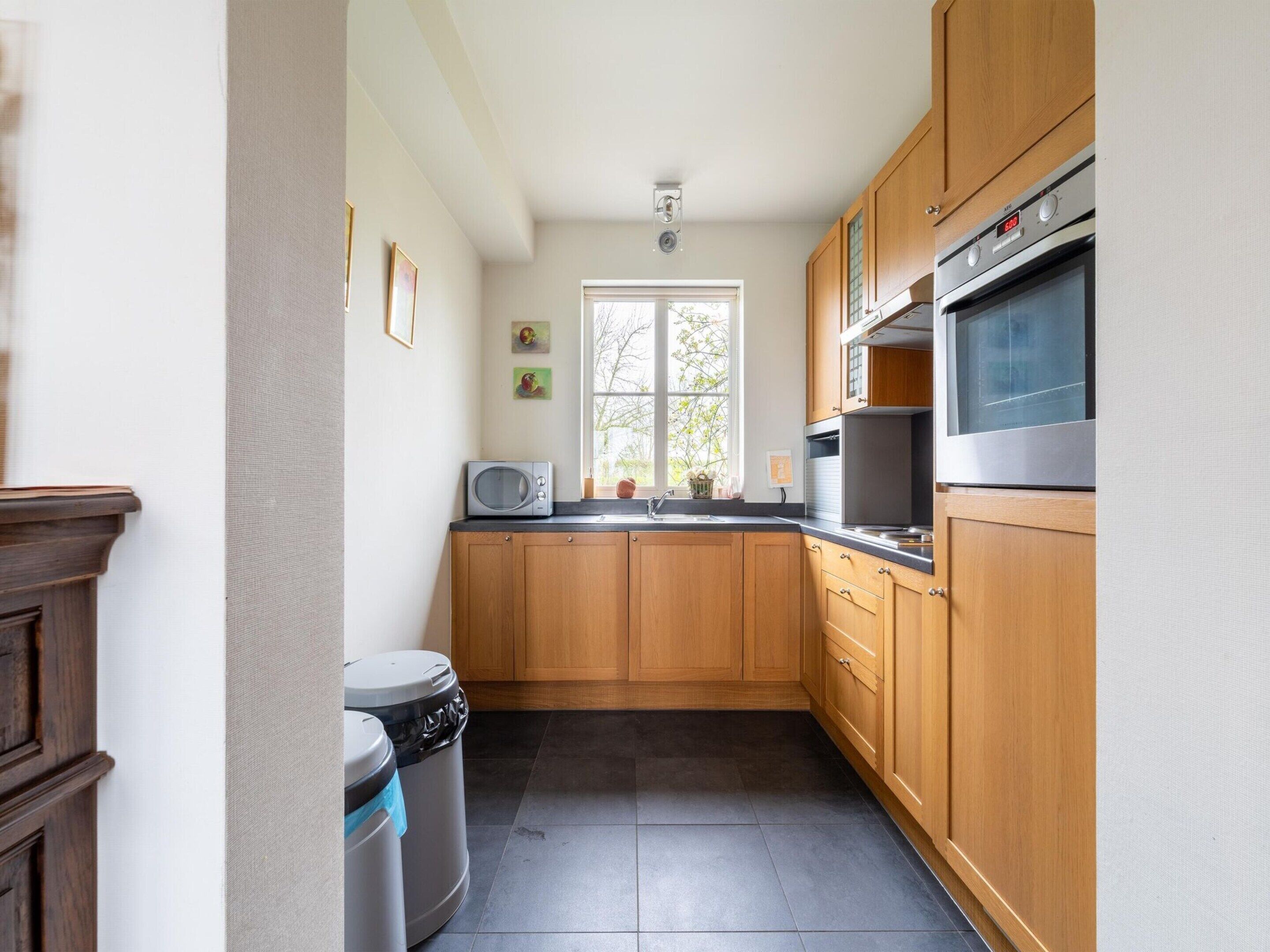 Une cuisine compacte dotée de meubles en bois, d’un four à micro-ondes et d’un four en acier inoxydable.