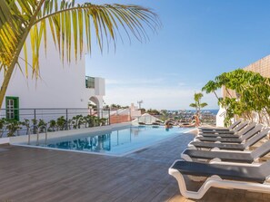 A rooftop pool with lounge chairs, a clear sky, and a view of the cityscape. - Belvilla by OYO Apartment Santa Cruz Detenerife (Adeje)