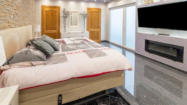A bedroom with a bed, a TV, and a fireplace. - Holiday Home in Verviers With Sauna (Verviers)