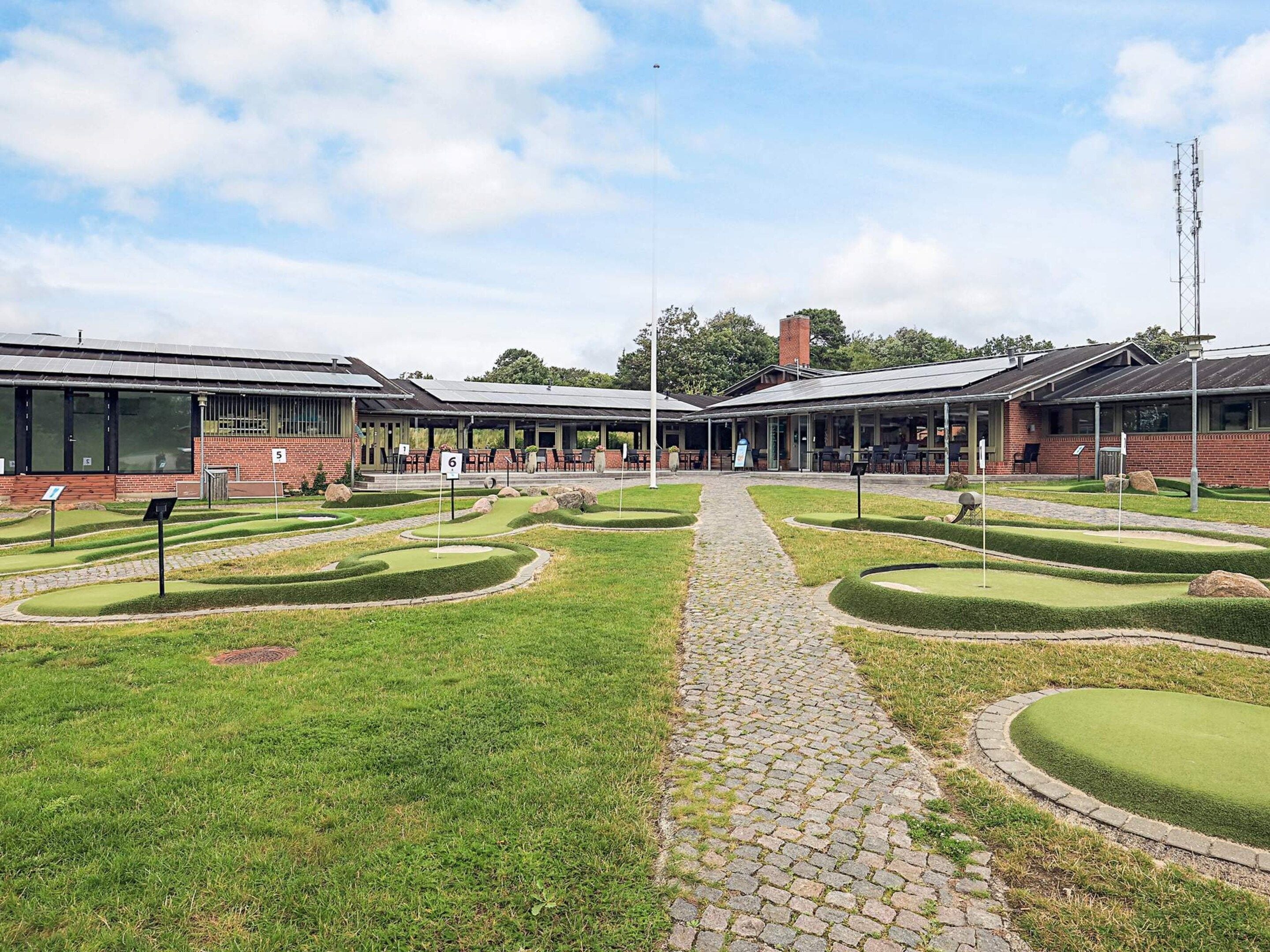 Un bâtiment à la façade en briques, doté de grandes fenêtres et d’un espace extérieur abrité avec des tables et des chaises.