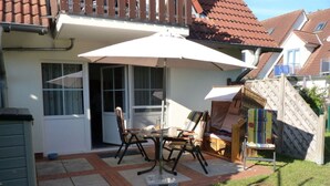 A patio with a table and chairs, a white umbrella, and a wooden fence. - Residential Complex "baltic Sea Waves" (Zingst)