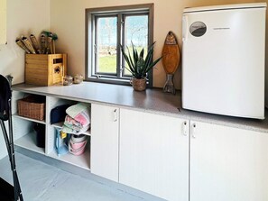 Eine kompakte Küche mit Kühlschrank, einem Fenster mit Aussicht und Stauraumschränken.