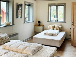 Un dormitorio con dos camas, una ventana con vistas, un radiador y una mesita de noche con lámpara.