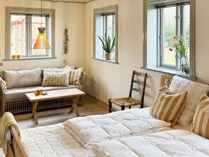 A cozy room with a sofa, a wooden table, a chair, and a bed. - 8 Person Holiday Home in Thyholm (Thyholm)