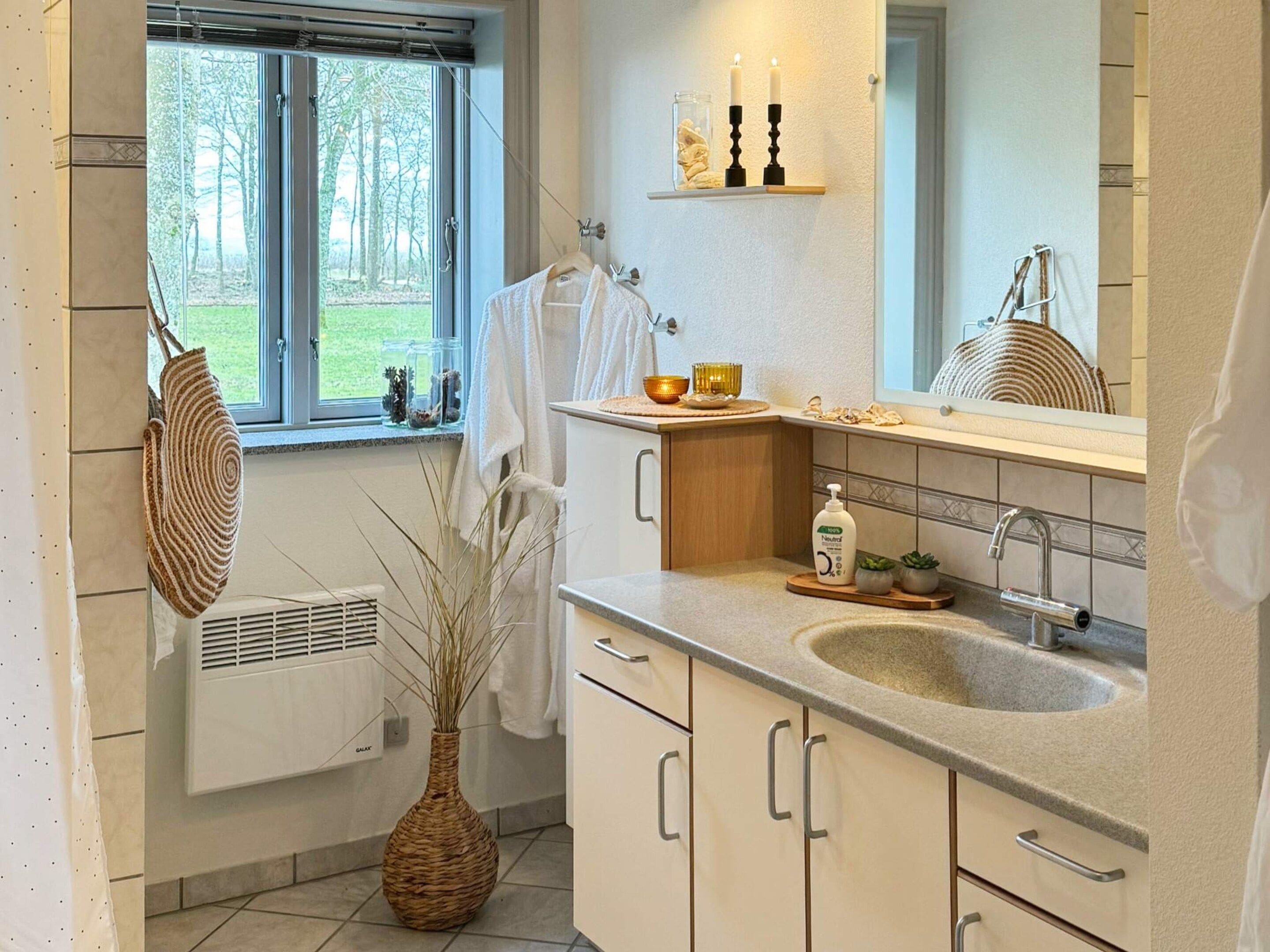 A modern bathroom with a large window, a sink, a mirror, and a towel rack.