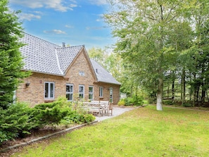 A brick house with a tiled roof, surrounded by a well-maintained lawn and trees. - 8 Person Holiday Home in Thyholm (Thyholm)
