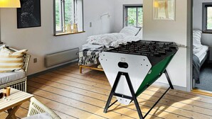 Una habitación acogedora con una cama, una mesa de fútbol y un ventanal con vistas a zonas verdes.