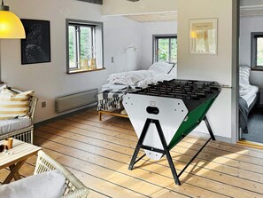 Ein gemütliches Zimmer mit einem Bett, einem Kicker und einem Fenster mit Blick auf Grünflächen.
