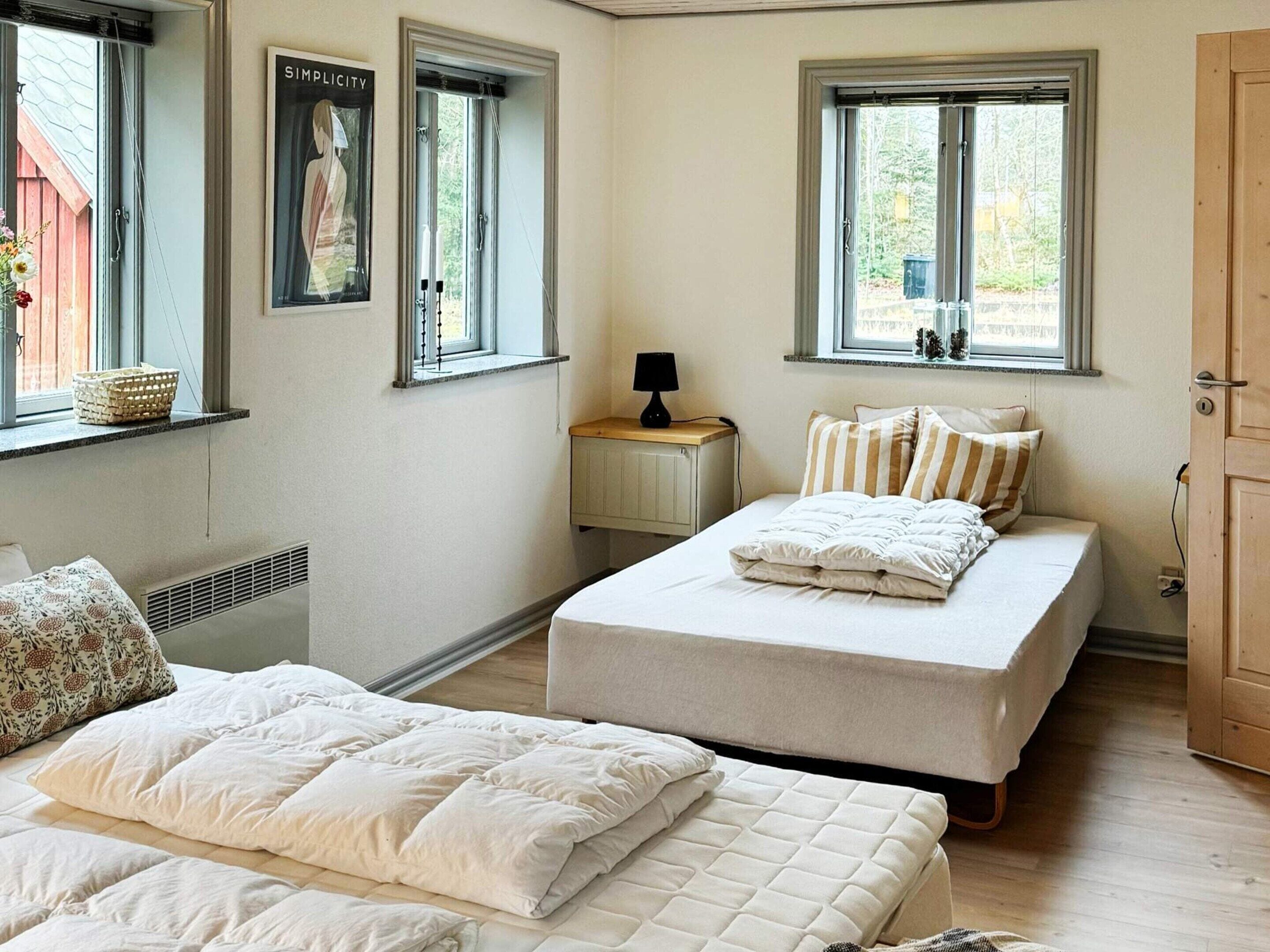 Une chambre avec deux lits, un radiateur, une fenêtre avec un rideau et une petite table avec une lampe.