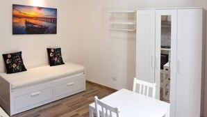 A room with a white sofa, a dining table, and a cabinet. - Pleasant Apartment in Alghero (Alghero)