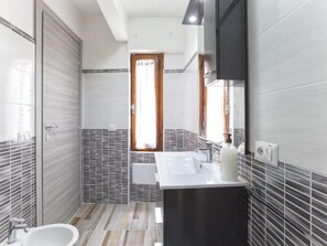 Ein modernes Badezimmer mit großem Spiegel, Waschbecken und Toilette.