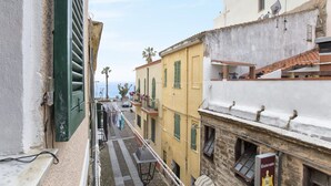 A narrow street with buildings on either side, a balcony with clothes hanging, and a sign for a restaurant. - Pleasant Apartment in Alghero (Alghero)