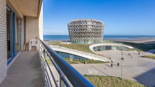 Un edificio moderno con un diseño esférico único, un balcón con vistas a la playa y un letrero de casino.