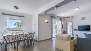 Ein modernes Wohnzimmer mit einer Couch, einem Essbereich mit Tisch und Stühlen sowie einem Fernseher.