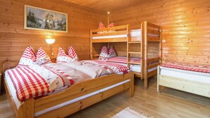 En stuga med träpanel, våningssängar, en tavla på väggen och en sänglampa.