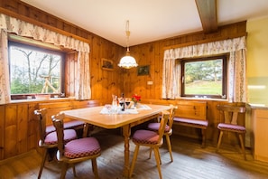 A wooden-paneled dining room with a table, chairs, and a hanging light fixture.