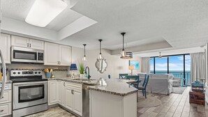 A modern kitchen with stainless steel appliances, a central island, and a dining area with a view. - BREATHTAKING VIEW! 3BR/2BA Condo Unit 8B Centrally Located In North Myrtle Beach (North Myrtle Beach)