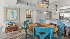 A dining area with a wooden table, blue chairs, and a hanging light fixture. - BREATHTAKING VIEW! 3BR/2BA Condo Unit 8B Centrally Located In North Myrtle Beach (North Myrtle Beach)