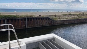Uitzicht vanaf een boot op een strand met een metalen hek en treden naar de kust.