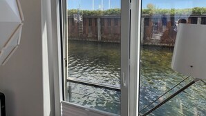 Uitzicht door een raam met een metalen hekwerk, een heldere lucht en vlaggen op de achtergrond.