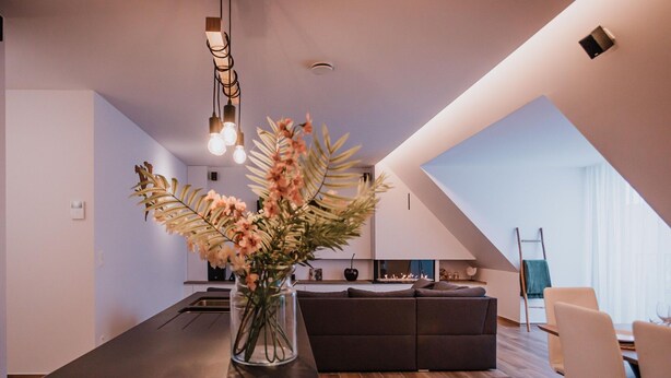 Eine moderne Küche mit Kochinsel, einem Essbereich mit Sofa und einem großen Fenster, das für natürliches Licht sorgt.