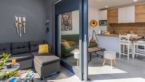 A modern living space with a sofa, ottoman, and a dining area with a table and chairs. - Apartment Good Vibes (Konavle)
