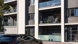 A modern building with multiple balconies, large windows, and a car parked in front. - Apartment Good Vibes (Konavle)