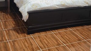 A bed with a patterned bedspread, a dark headboard, and a wooden floor. - c'est lavie ultra apartments (Rodney Bay)