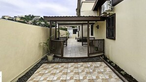 A covered patio area with a tiled floor, a pergola, and a small garden with a potted plant. - c'est lavie ultra apartments (Rodney Bay)
