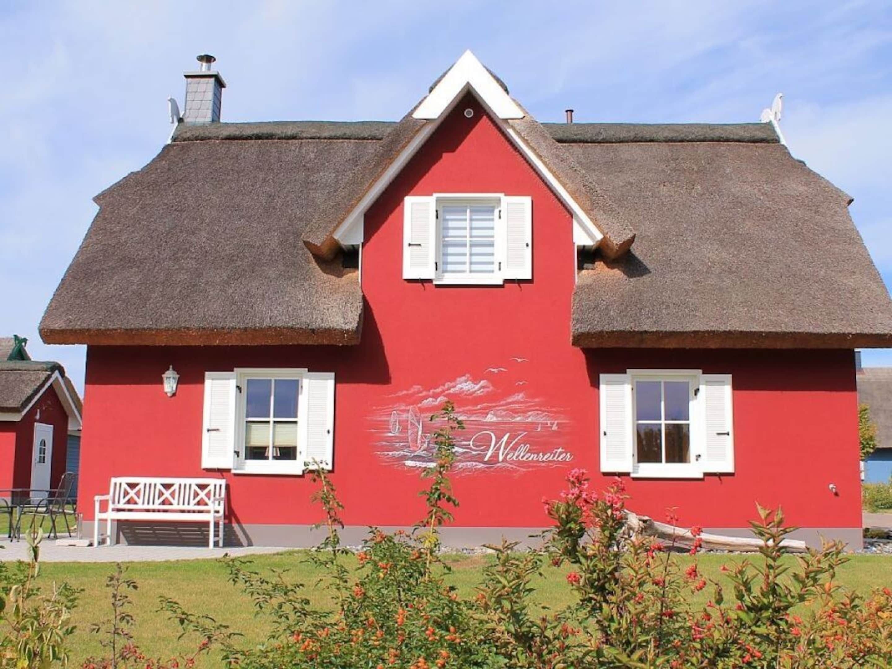 A red building with white shutters and a thatched roof.