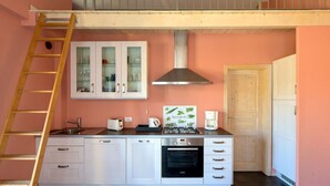 A kitchen with white cabinets, a stainless steel range hood, a Bosch oven, a coffee maker, and a wooden ladder. - Holiday Apartment Monte Faudo (Cipressa)