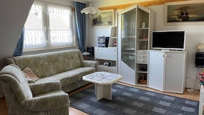 A living room with a sofa, a coffee table, a TV, and a cabinet with shelves. - Attractive Apartment Near Town Center (Wangerland)