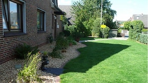 A residential garden with a well-maintained lawn, a pathway, and various plants. - Attractive Apartment Near Town Center (Wangerland)