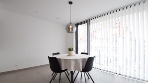 Un comedor moderno con una mesa redonda, sillas negras, una lámpara colgante y vistas amplias a través de grandes ventanales.