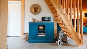 A wooden staircase leading to a loft area with a blue cabinet containing kitchenware and a microwave. - Holiday Home Near the sea and Dunes (Ouddorp)