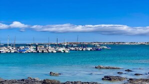 A marina with boats docked, calm water, and a clear sky.