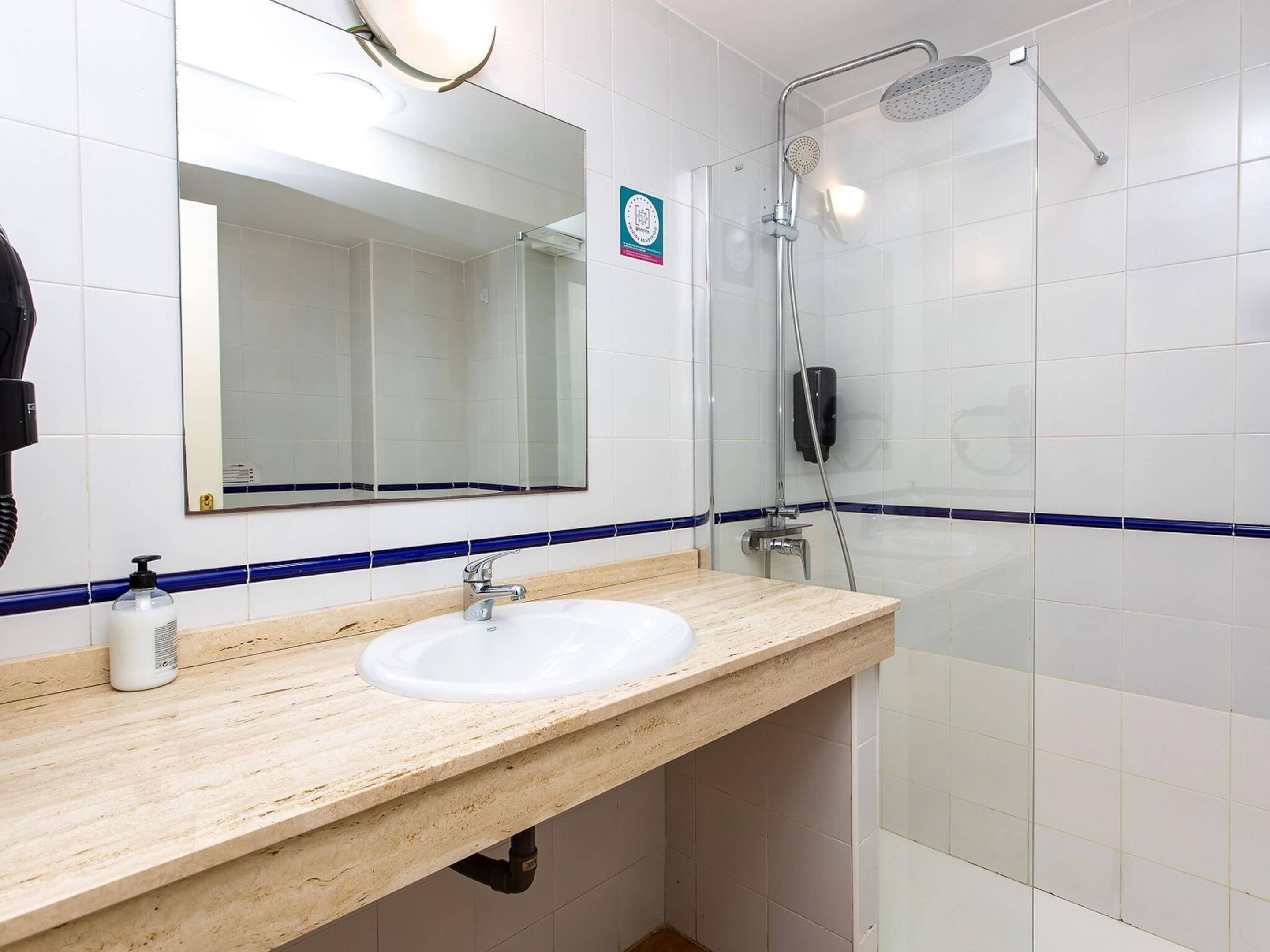 A bathroom with a sink, mirror, and shower.