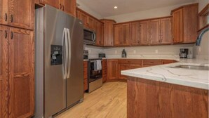 Una cocina moderna con armarios de madera, electrodomésticos de acero inoxidable y encimera de mármol.