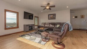 Una sala de estar amplia con un sofá modular grande, una mesa de centro y un ventilador de techo.
