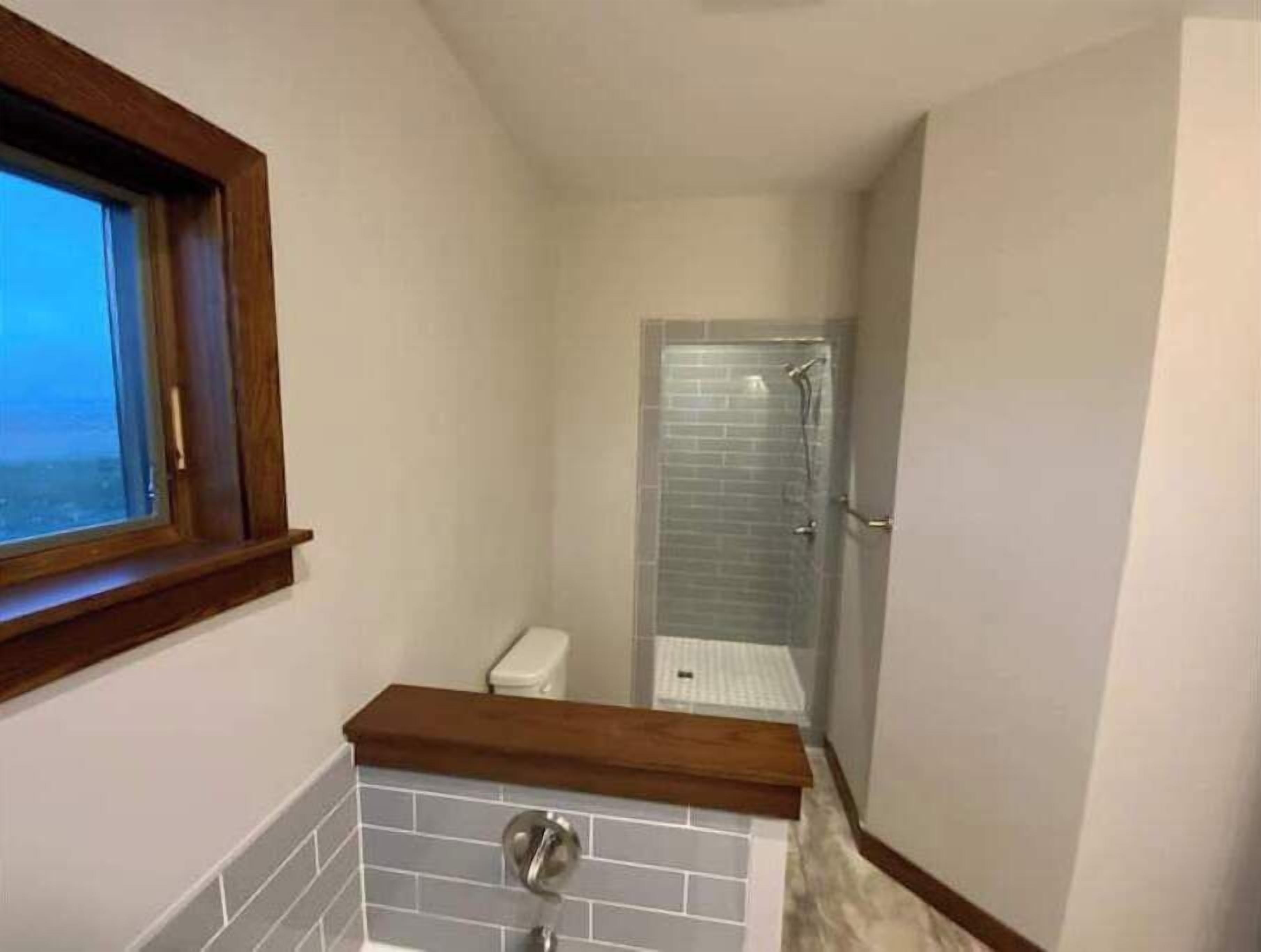 A bathroom with a window, a shower, and a toilet.